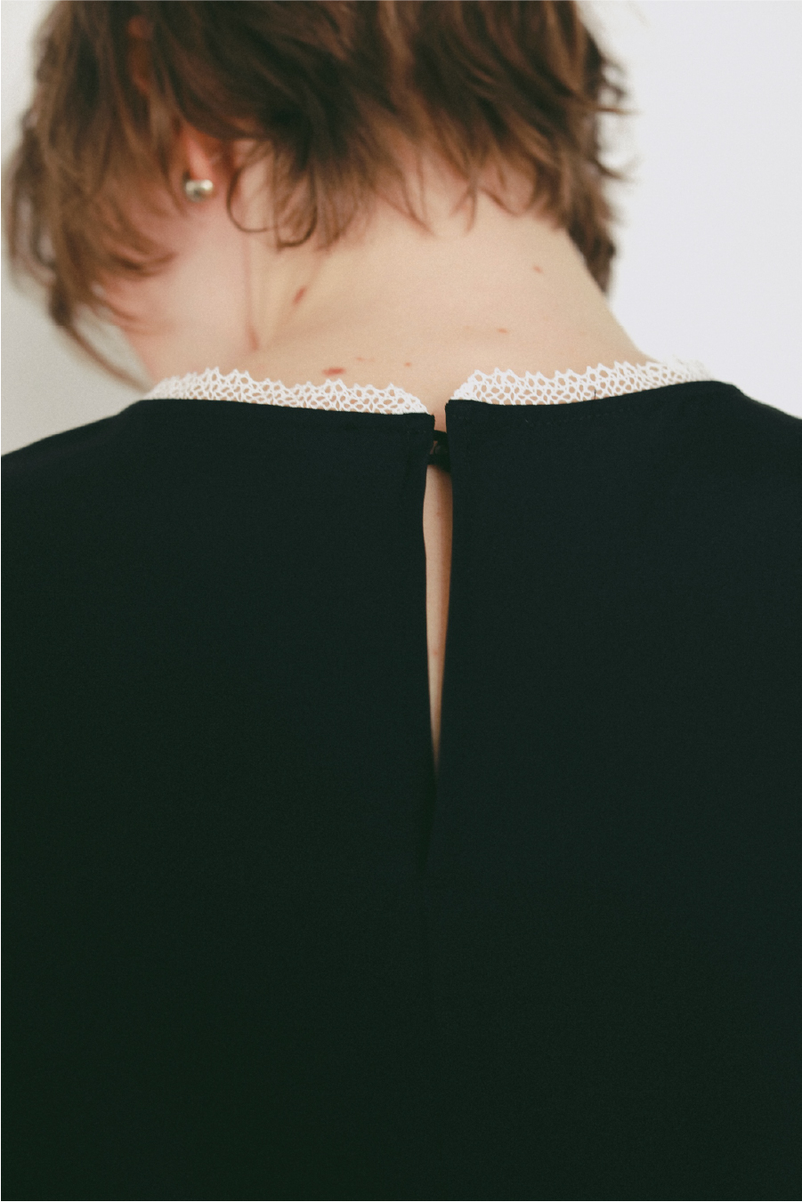 レーストリムブラウスを着用した女性の後ろ姿の画像