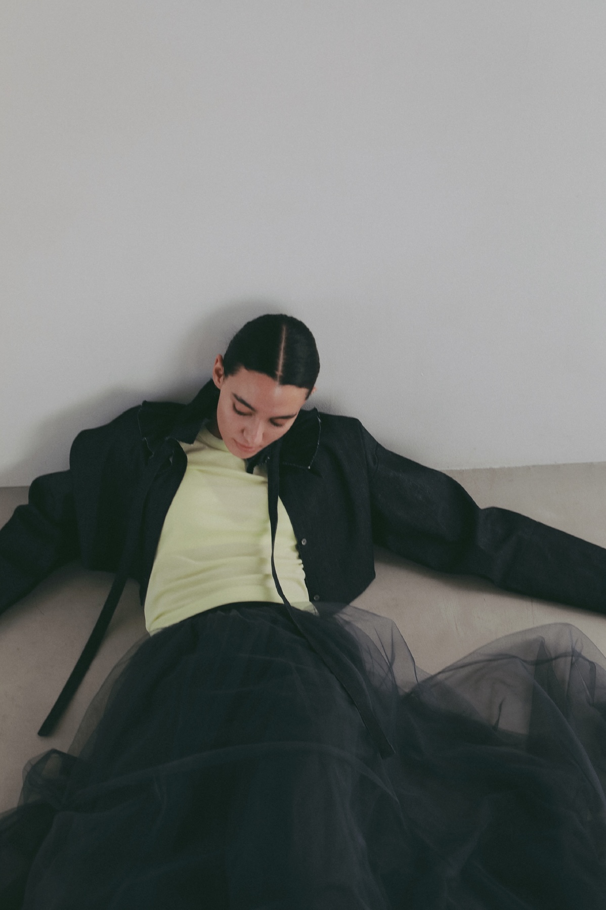 ブラックのジャケット・ライムグリーンのトップス・ブラックのスカートを着用した女性の画像