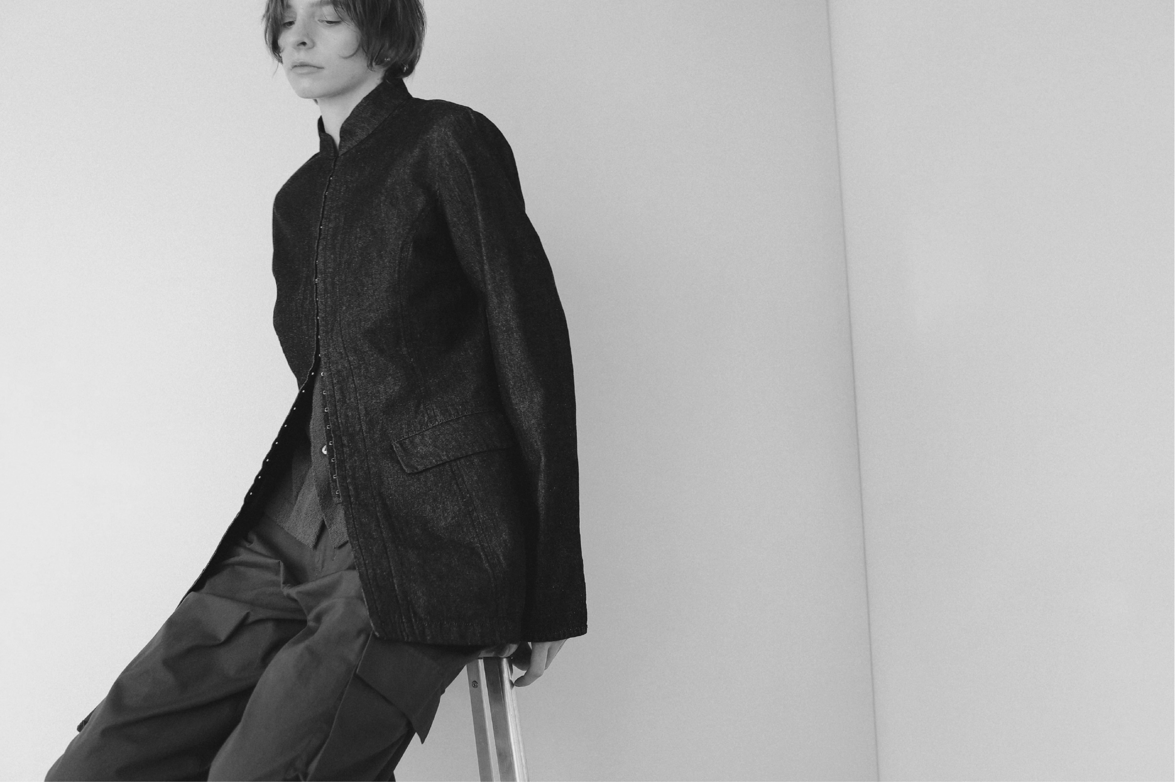 ブラックのジャケット・カーキのトップス・カーキのパンツを着用した女性のモノクロ画像