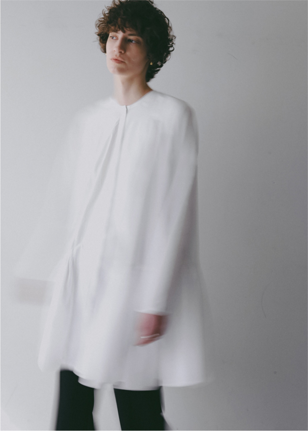 ホワイトのブラウス・ブラックのパンツを着用した女性の画像