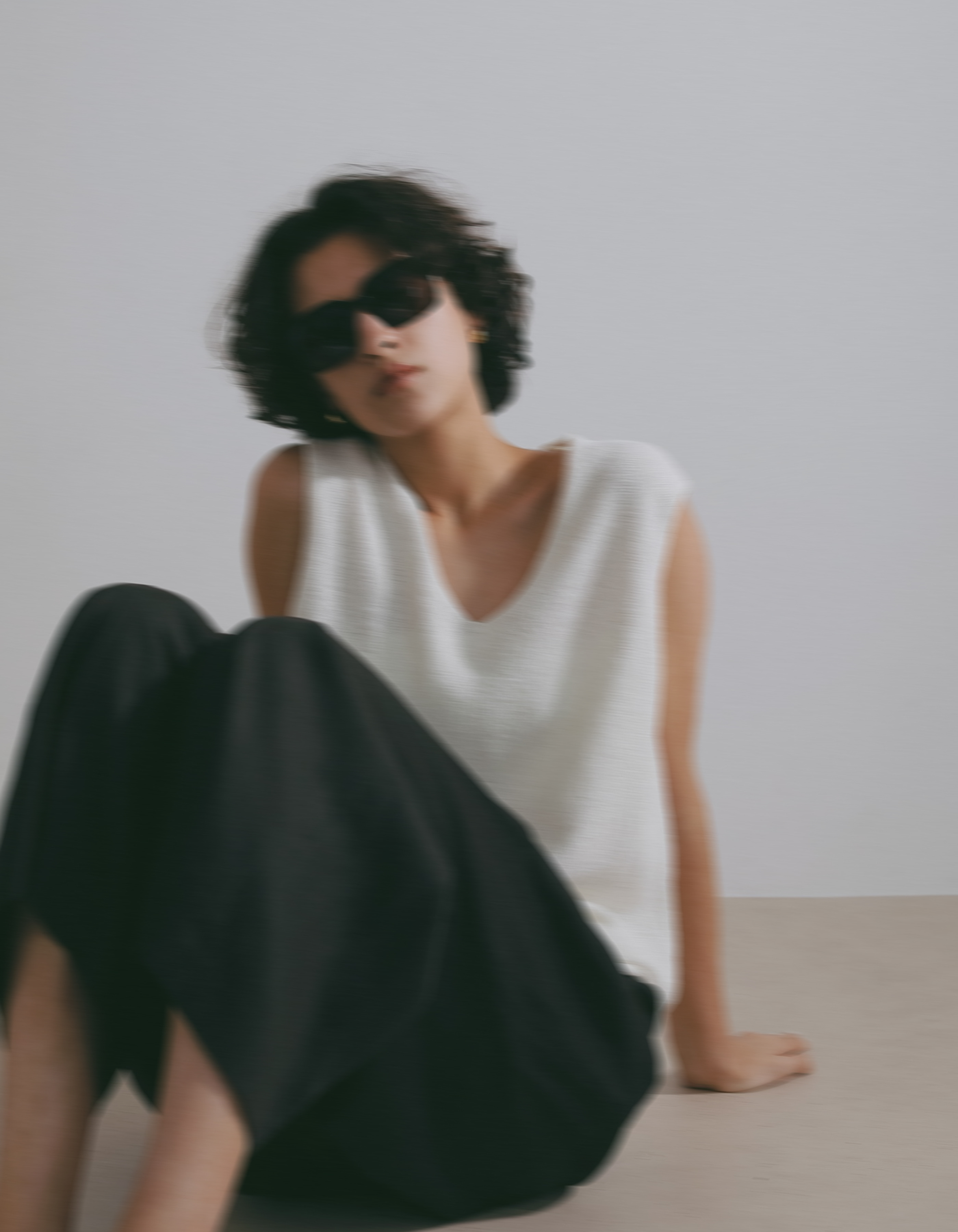サングラス・ホワイトのトップス・ブラックのパンツを着用した女性