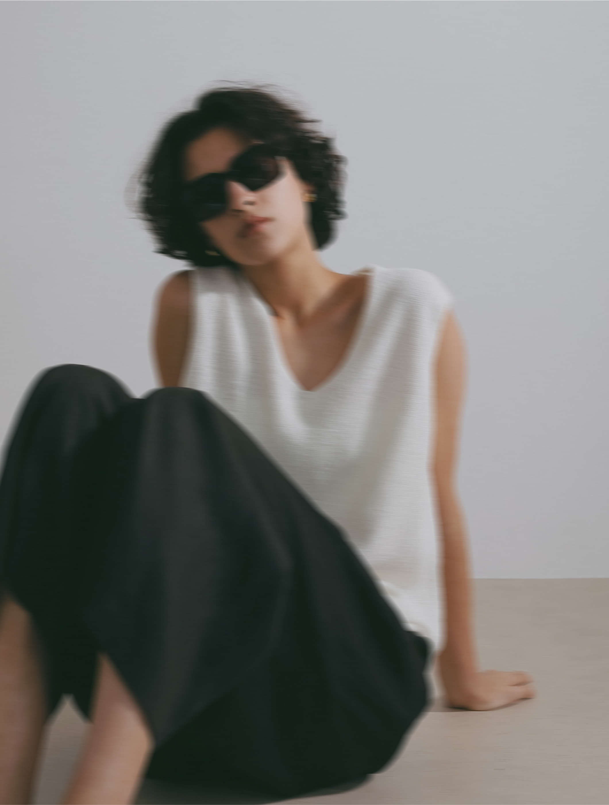 サングラス・ホワイトのトップス・ブラックのパンツを着用した女性